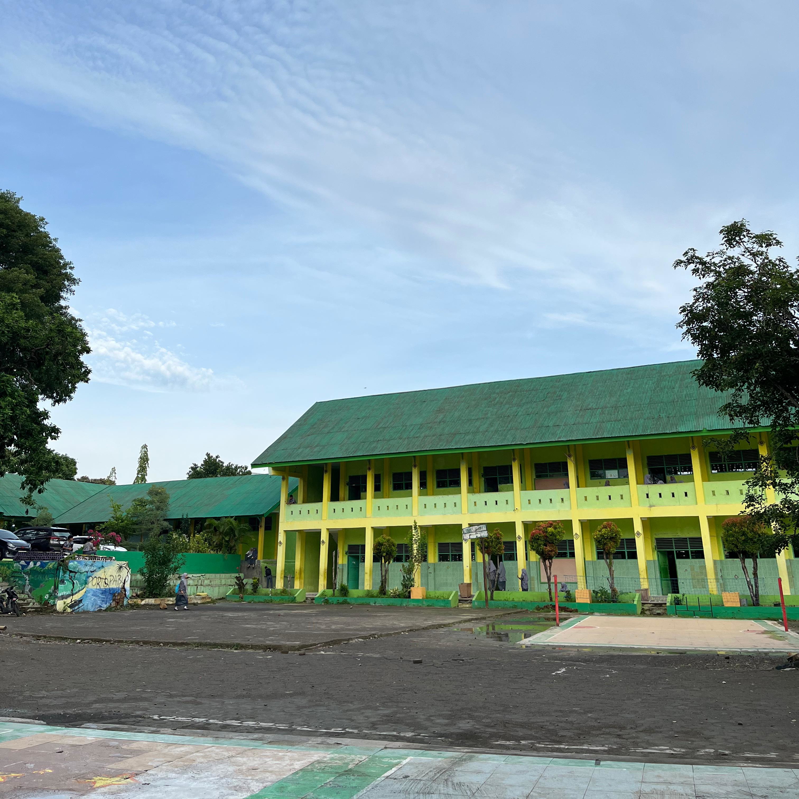 Gedung Madrasah Aliyah Negeri Jeneponto dengan siswa-siswi belajar di halaman sekolah pada siang hari